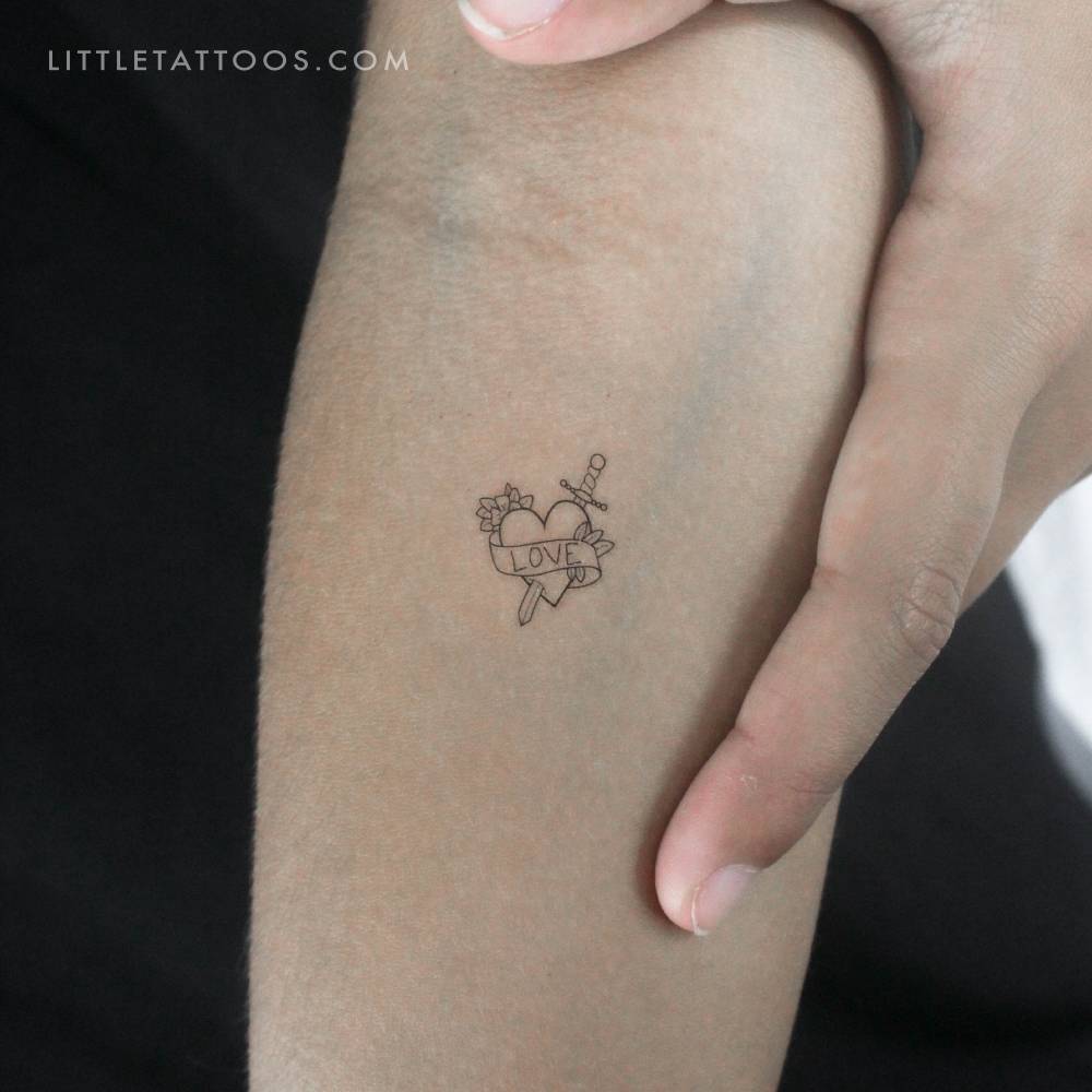 Fine line style heart and sword temporary tattoo located on the inner forearm.