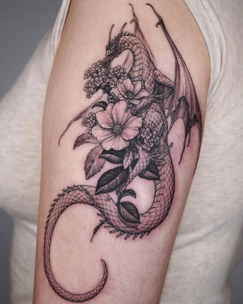 Tattoo of a dragon and flowers located on the upper arm.