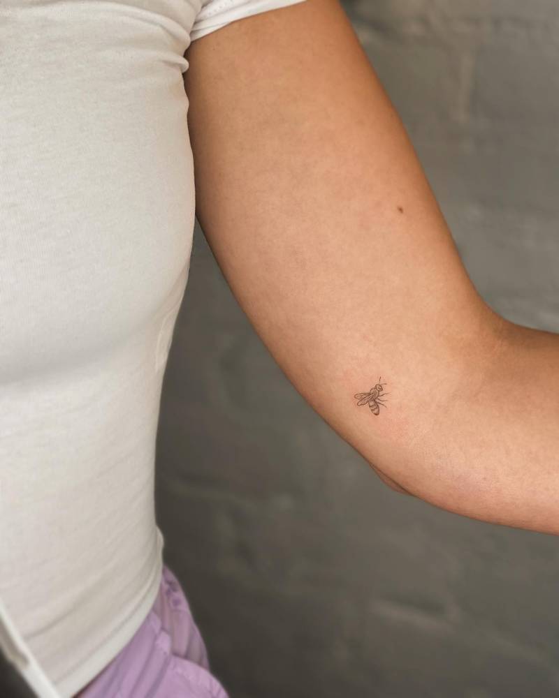 Tiny minimalistic bee tattoo placed on the inner arm.