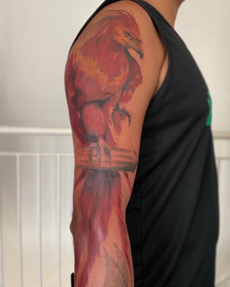 Watercolor style Fawkes tattoo located on the upper arm.
