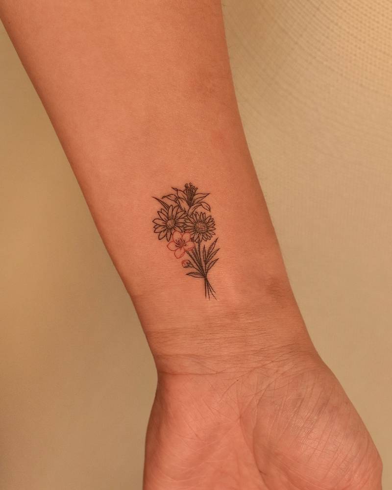 Fine line style flower bouquet tattoo located on the wrist.