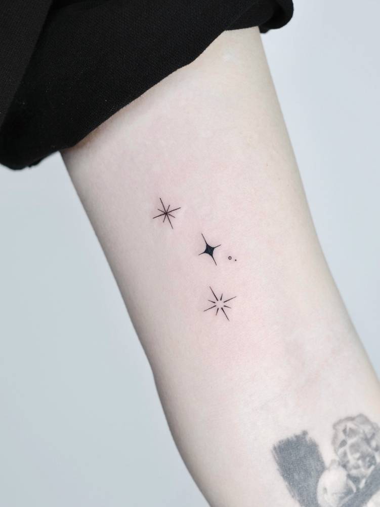 Sparkling stars tattoo done on the inner arm, minimalistic style.