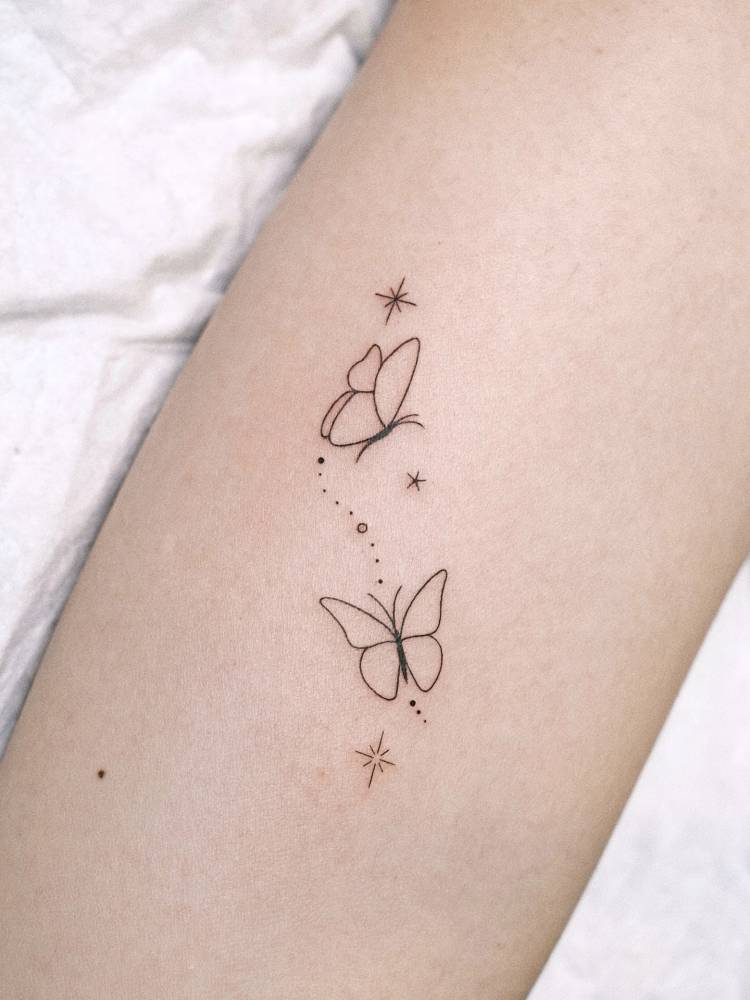 Fine line style butterfly couple tattoo placed on the inner arm.