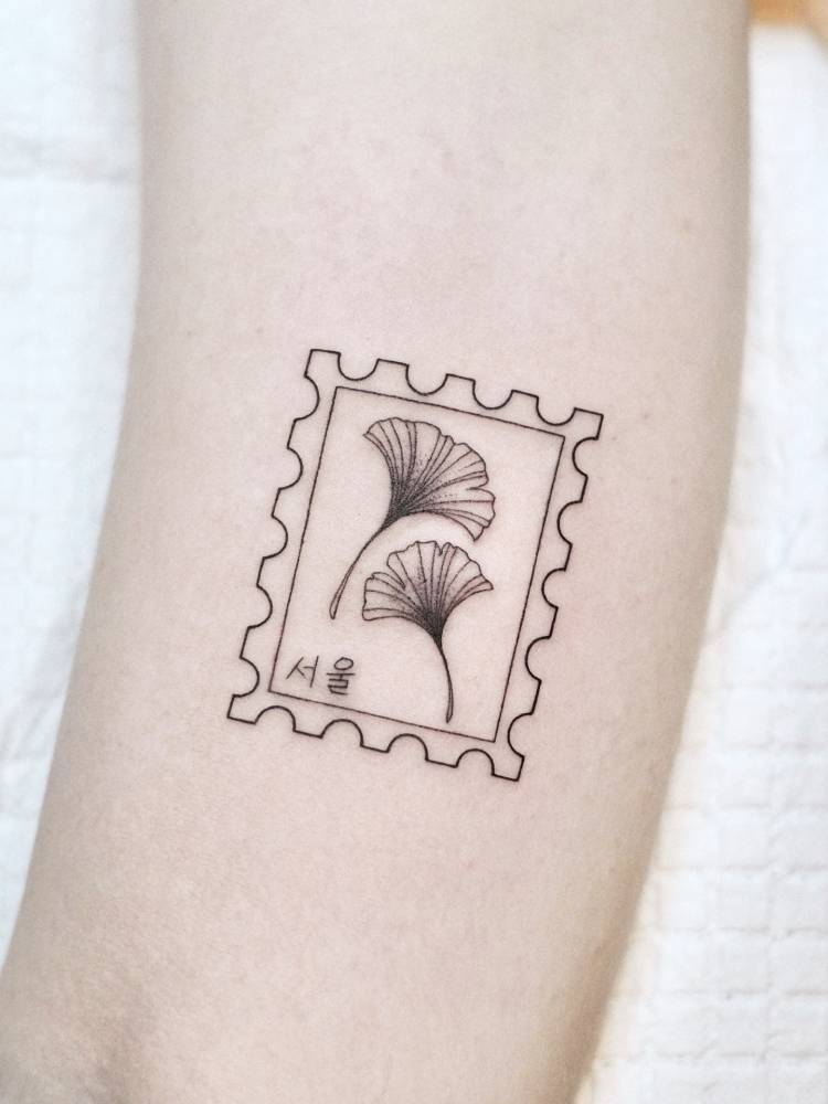 Ginkgo leaves stamp tattoo located on the inner arm.