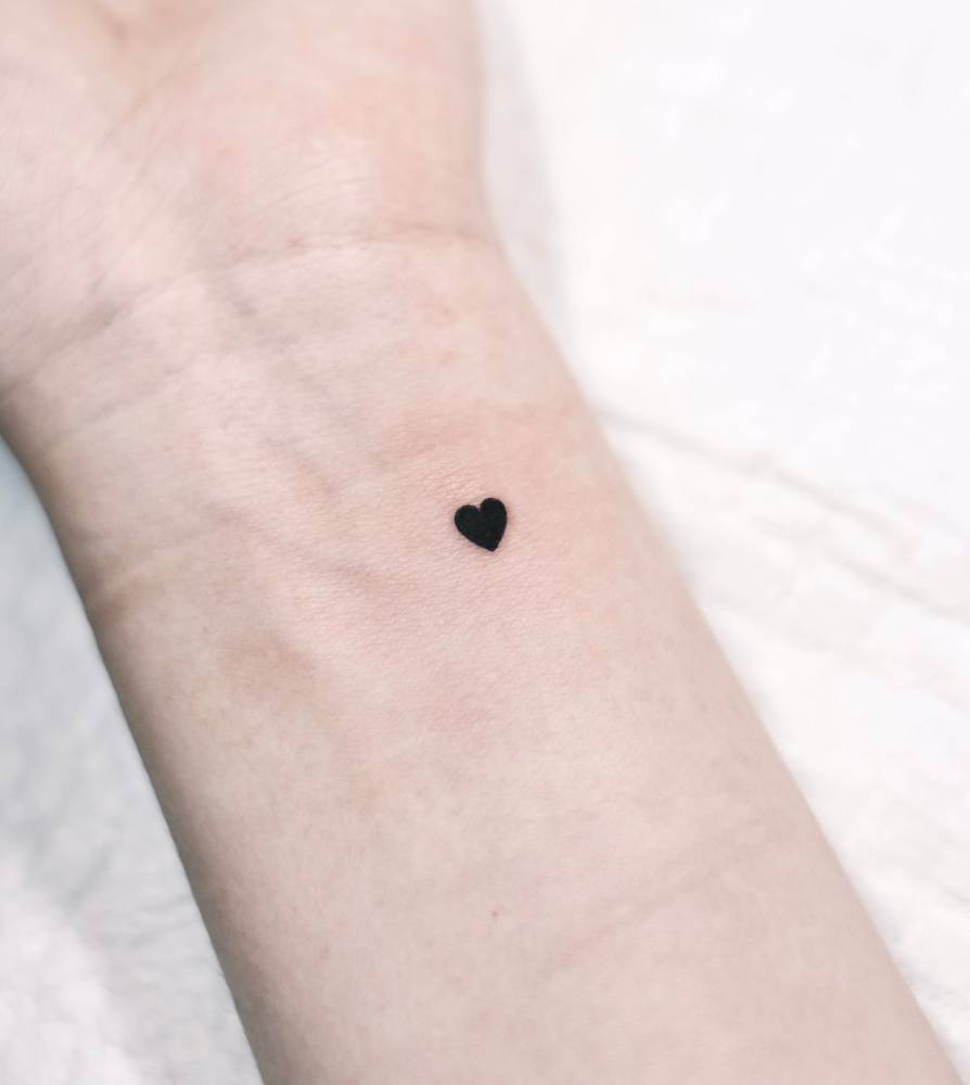 Tiny minimalistic heart tattoo located on the wrist.