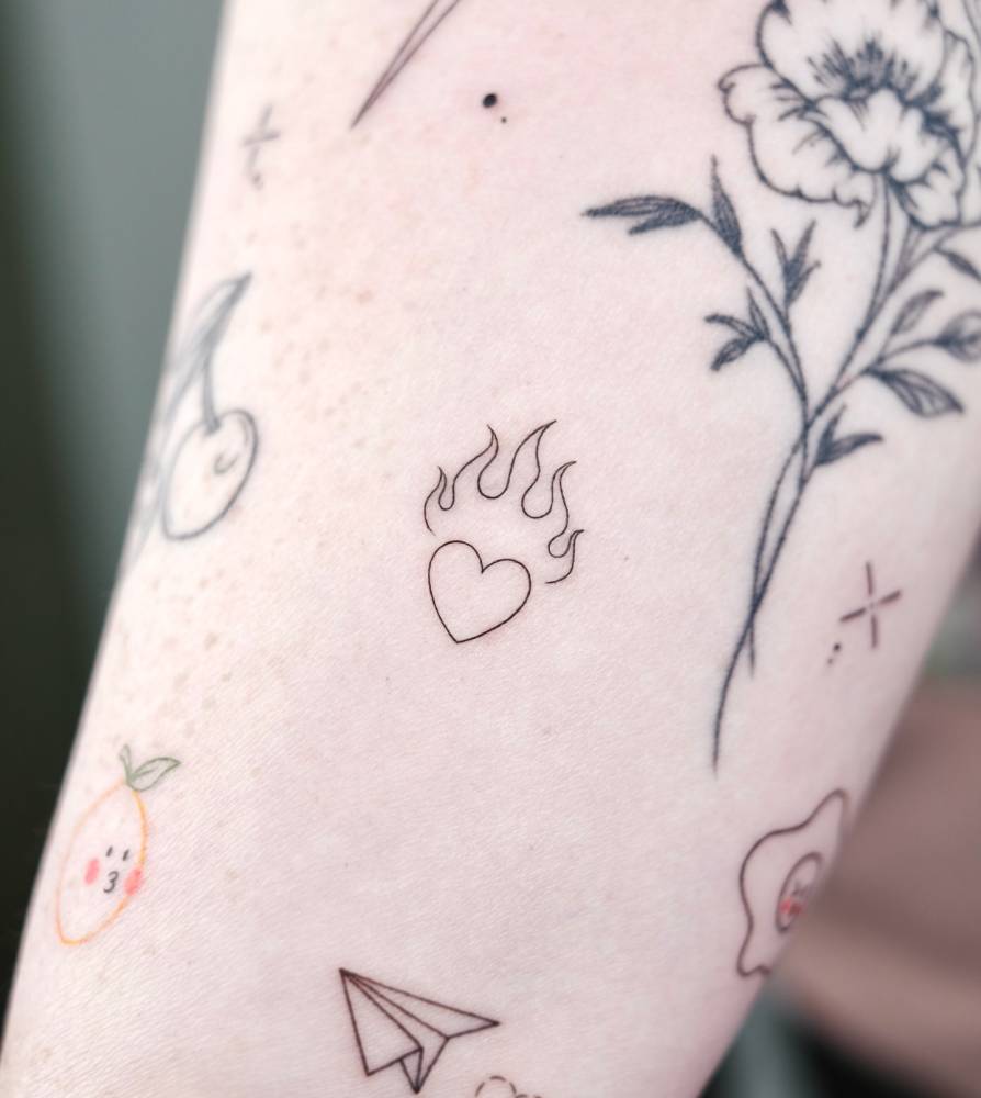 Tiny minimalistic flaming heart tattoo located on the inner forearm.
