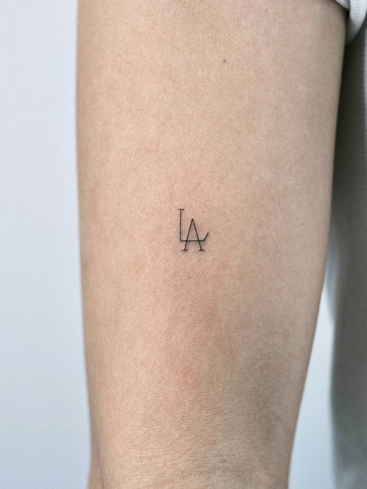 "LA" lettering tattoo located on the upper arm.