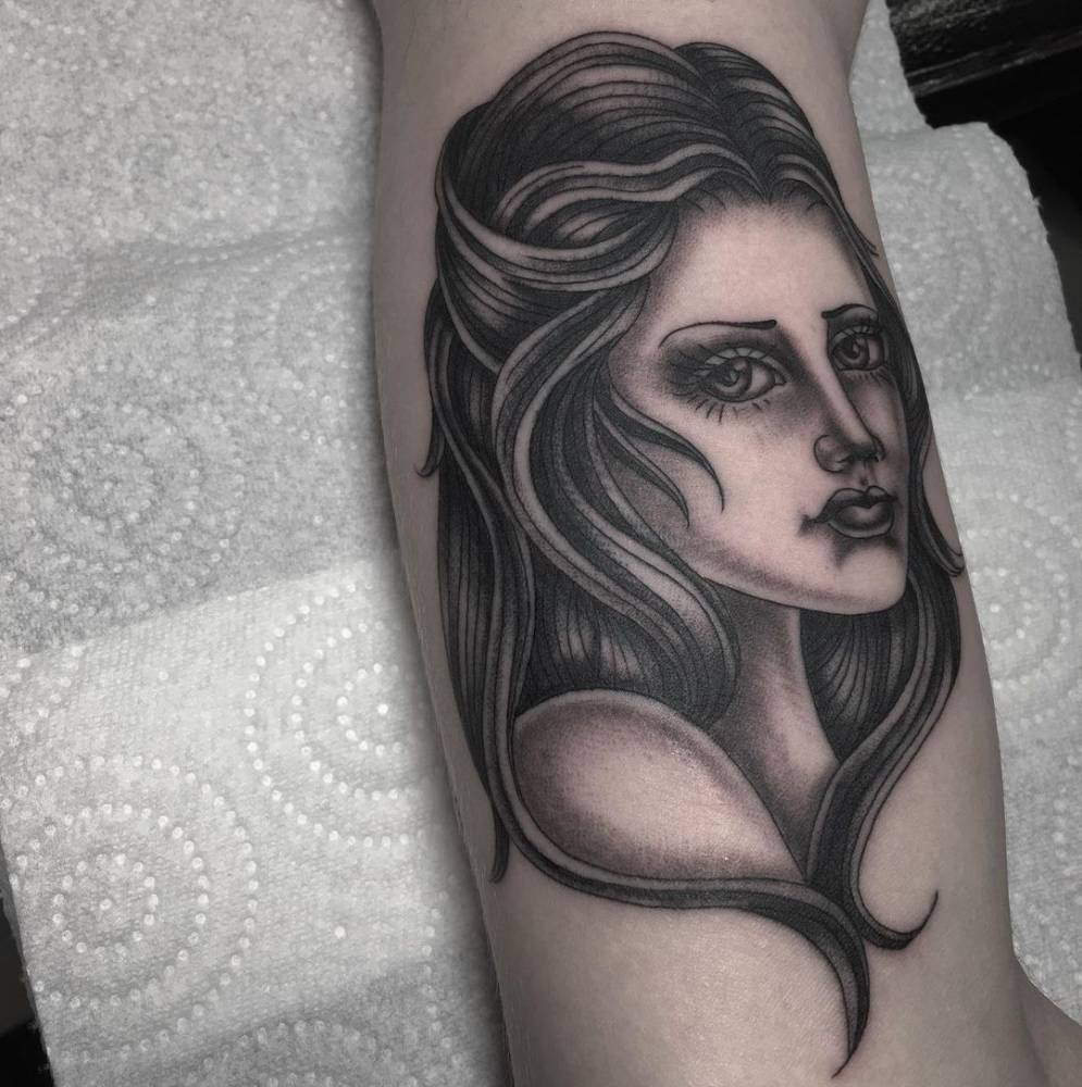 Traditional style woman portrait tattoo on the inner arm.
