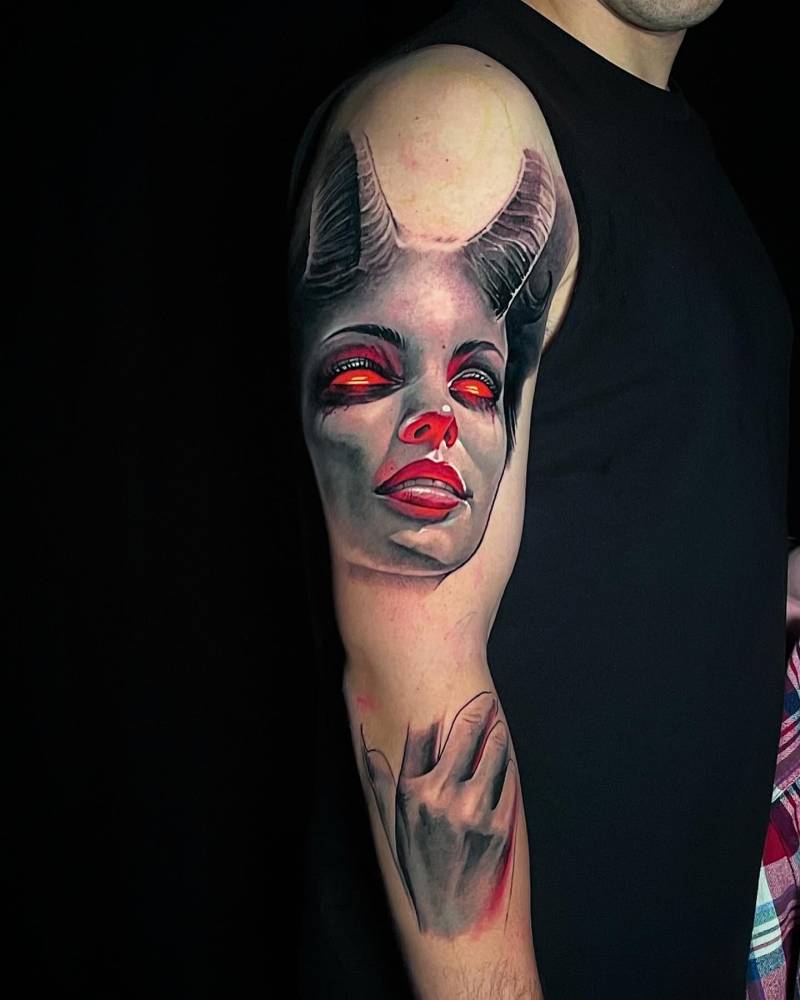 She devil portrait tattoo in realistic style located on the upper arm.