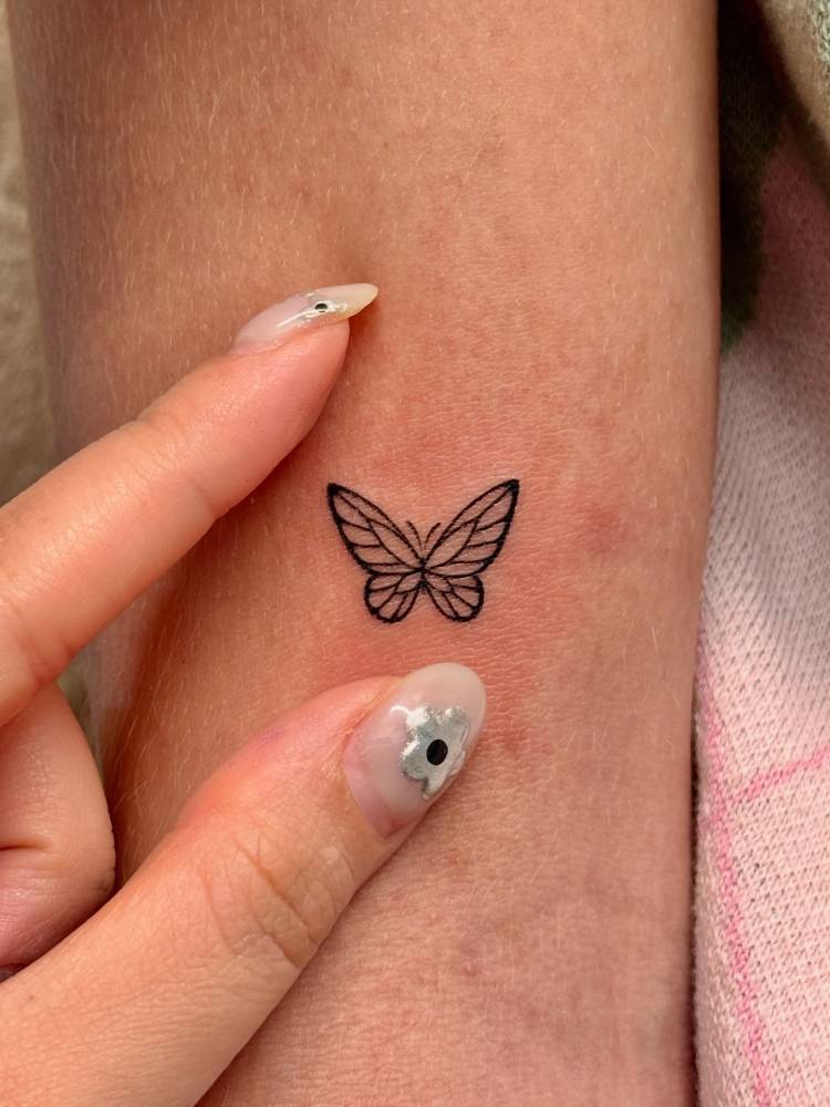 Fine line style butterfly tattoo placed on the bicep.