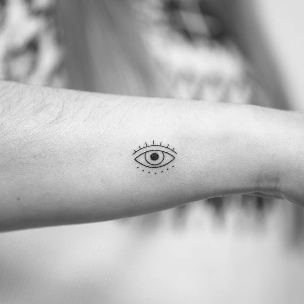 Mnimalistic evil eye tattoo located on the wrist.