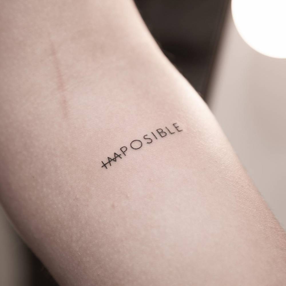 Word "impossible" tattooed on the inner forearm.