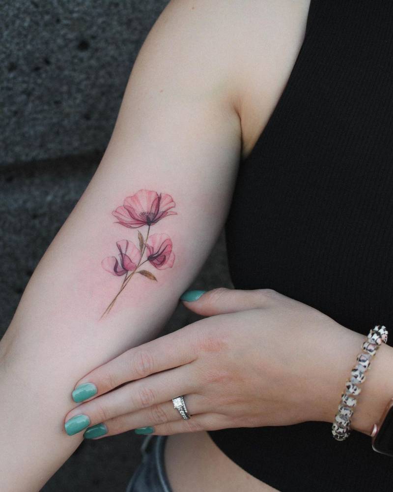 Poppy and sweet pea flowers tattooed on the inner arm.