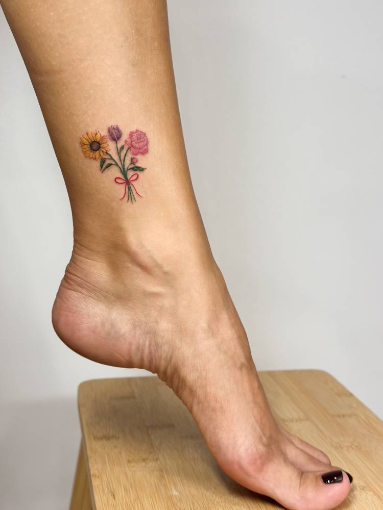 Flower bouquet tattoo in watercolor style located on the ankle.