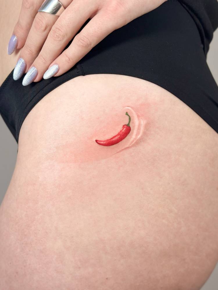 Red chili pepper tattoo located on the hip, illustrative style.