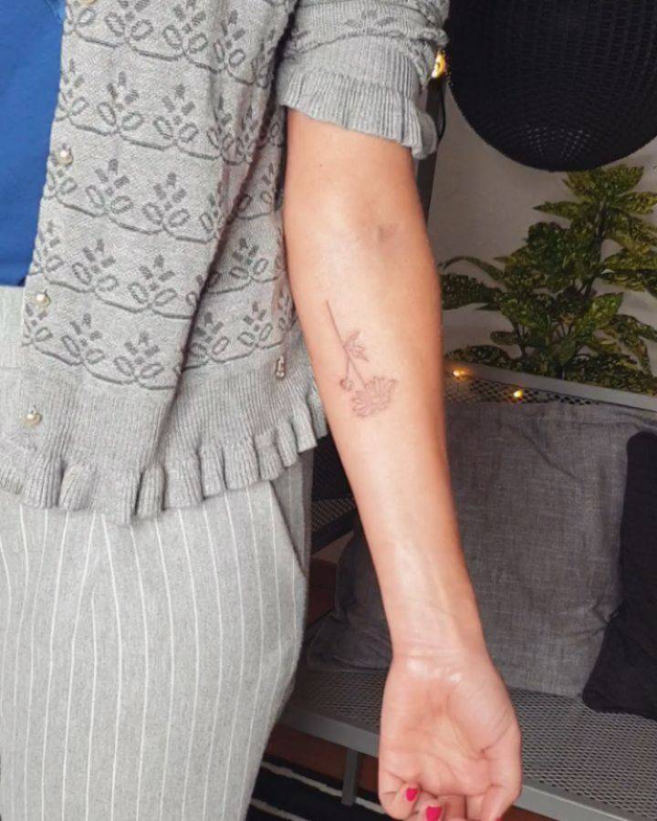Fine line daisy flower tattoo on the inner forearm.