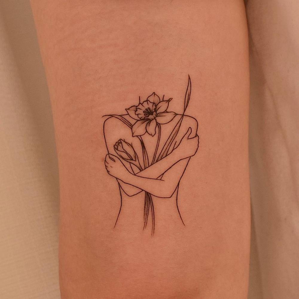 Fine line flower head woman tattoo on the tricep