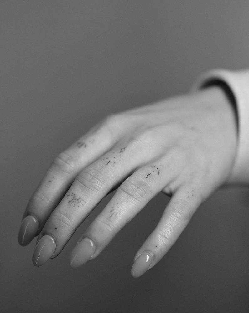 Fine line style ornaments tattooed on the fingers.