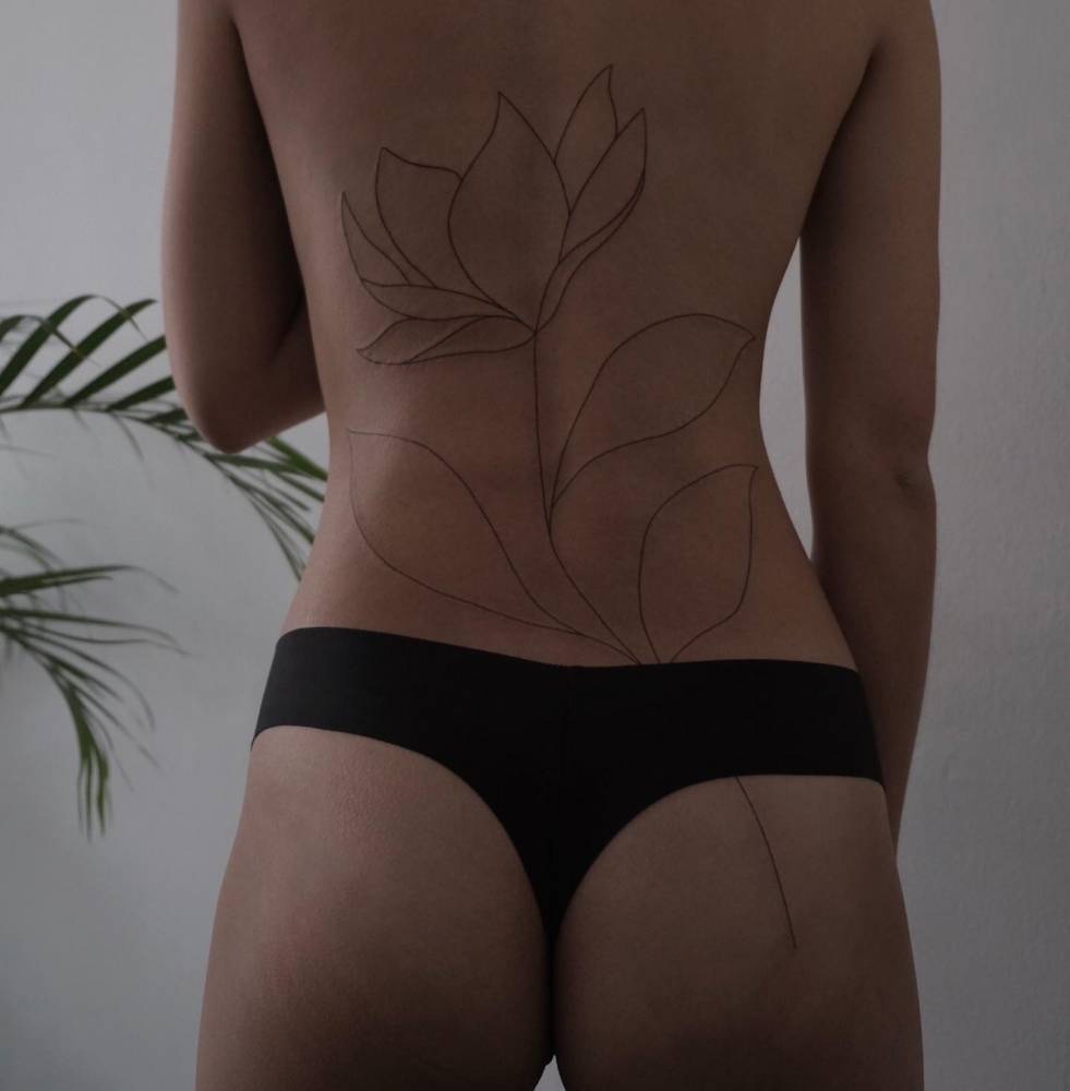 Line art lotus flower tattoo located on the back.
