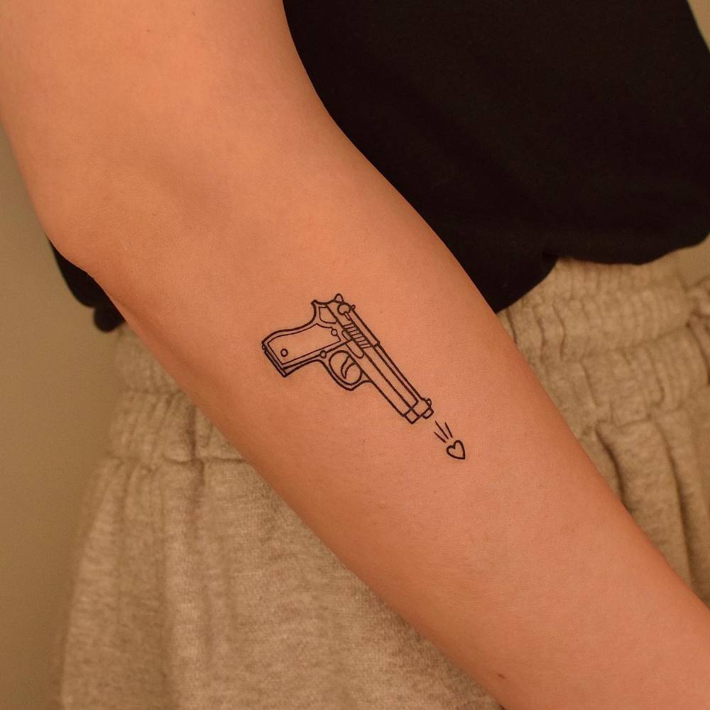 Line art gun tattoo located on the forearm.