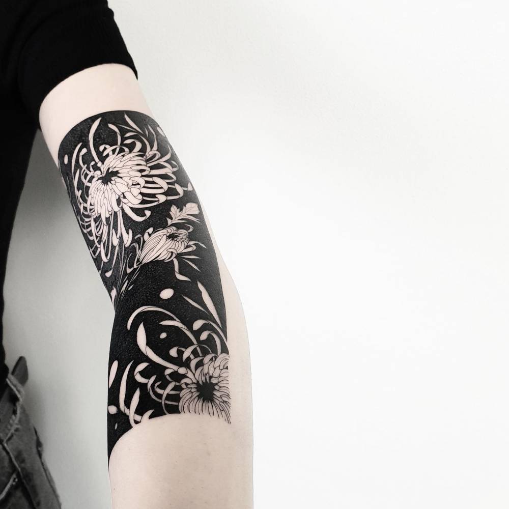 Chrysanthemums tattoo located on the arm, blackwork style.
