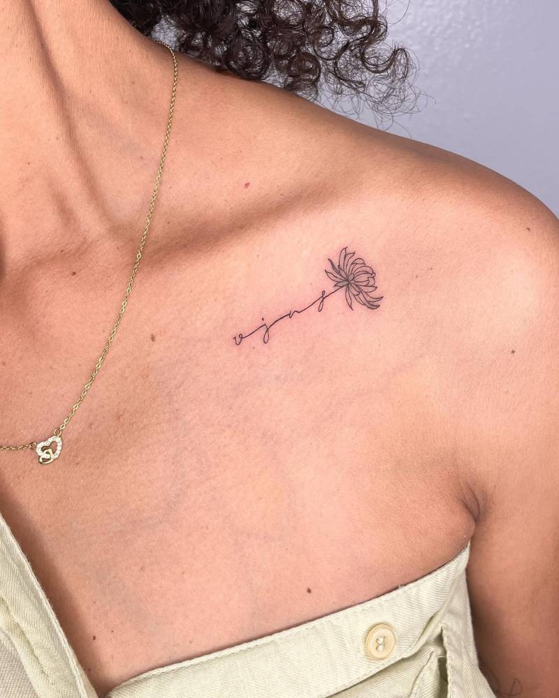 Fine line initials and chrysanthemum tattoo located on the collarbone.