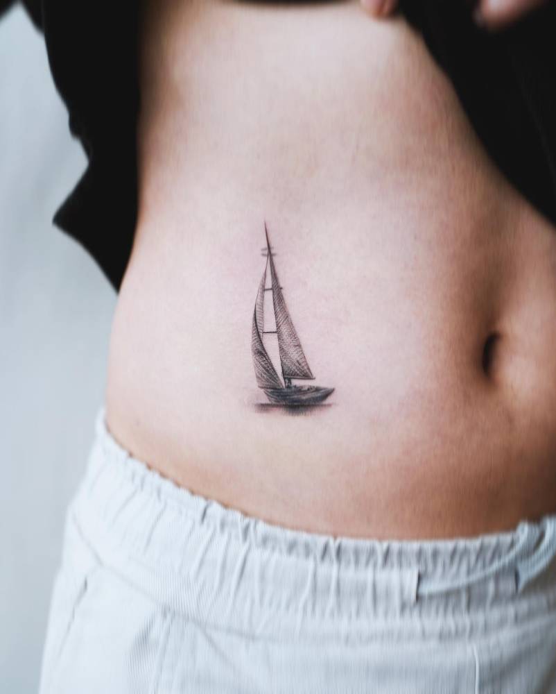 Micro-realistic style sailboat tattoo located on the waist.