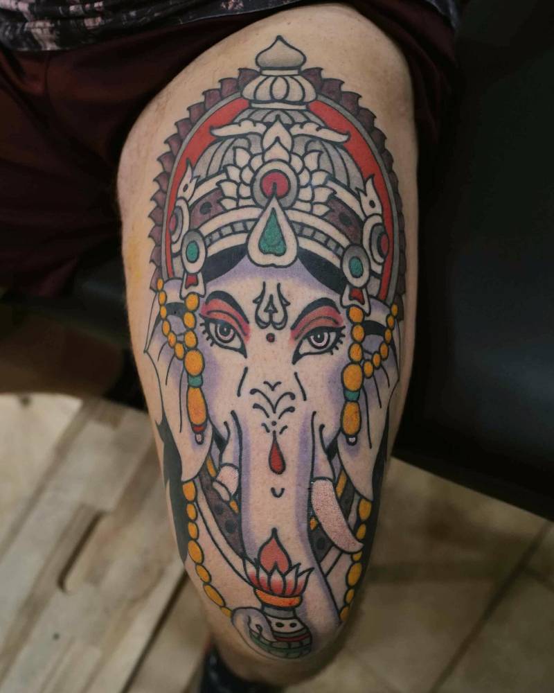 Ganesha portrait tattoo in traditional style located on the thigh.