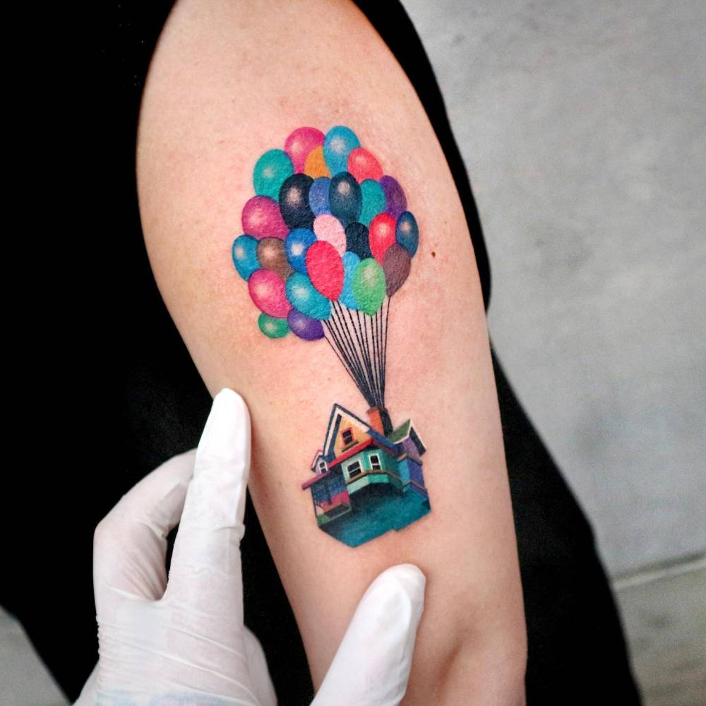 Pop art style 'Up' house tattoo located on the upper arm.