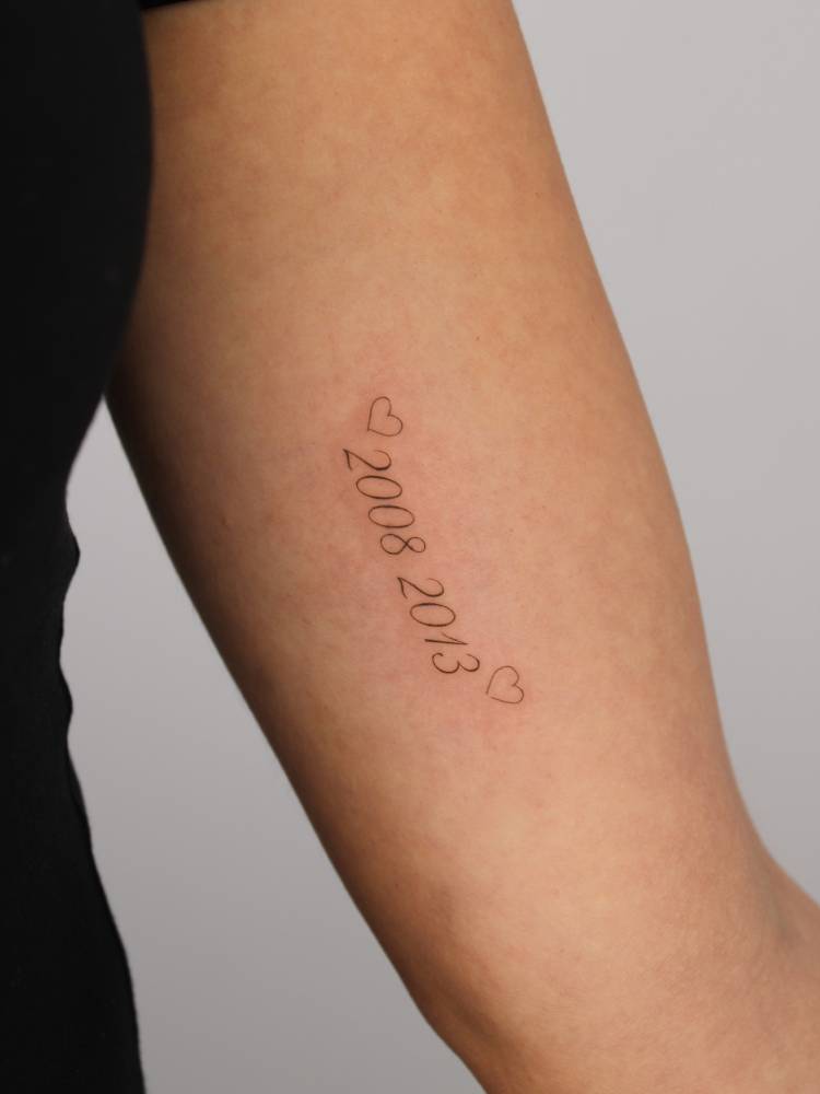Birth years "2008" and "2013" tattooed on the inner arm.