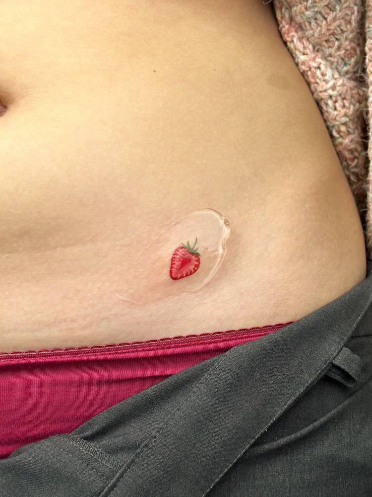Strawberry tattoo placed on the pelvis, done in illustrative style.