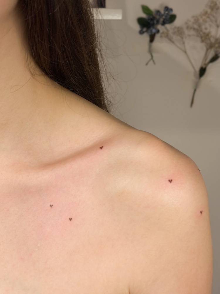 Tiny heart freckles tattoo located on the shoulder.