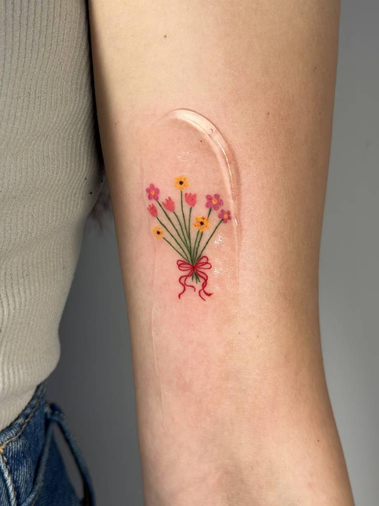 Flower bouquet tattoo in illustrative style placed on the inner arm.