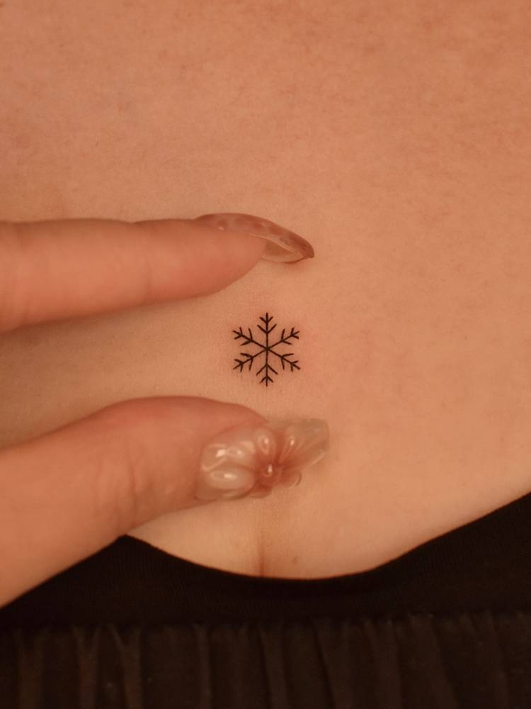 Fine line style snowflake tattoo located on the sternum.