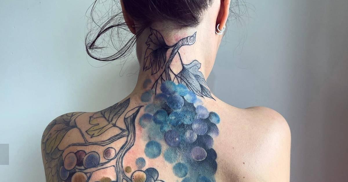 Watercolor style grapes tattoo located on the back.