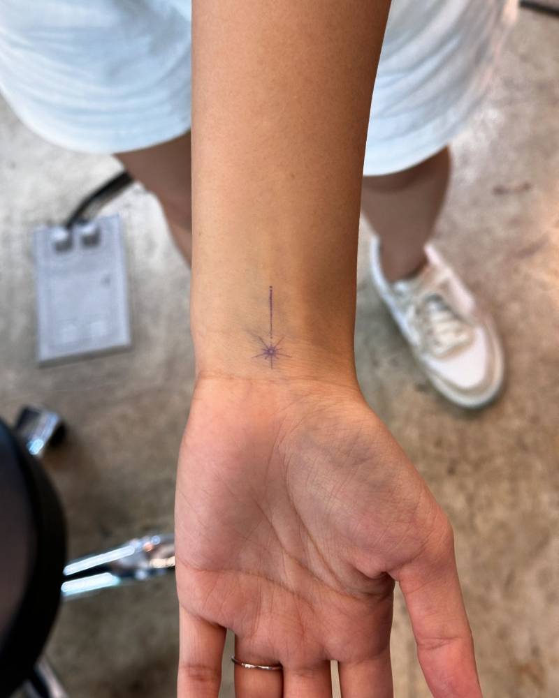 Minimalistic style star wand tattoo located on the wrist.