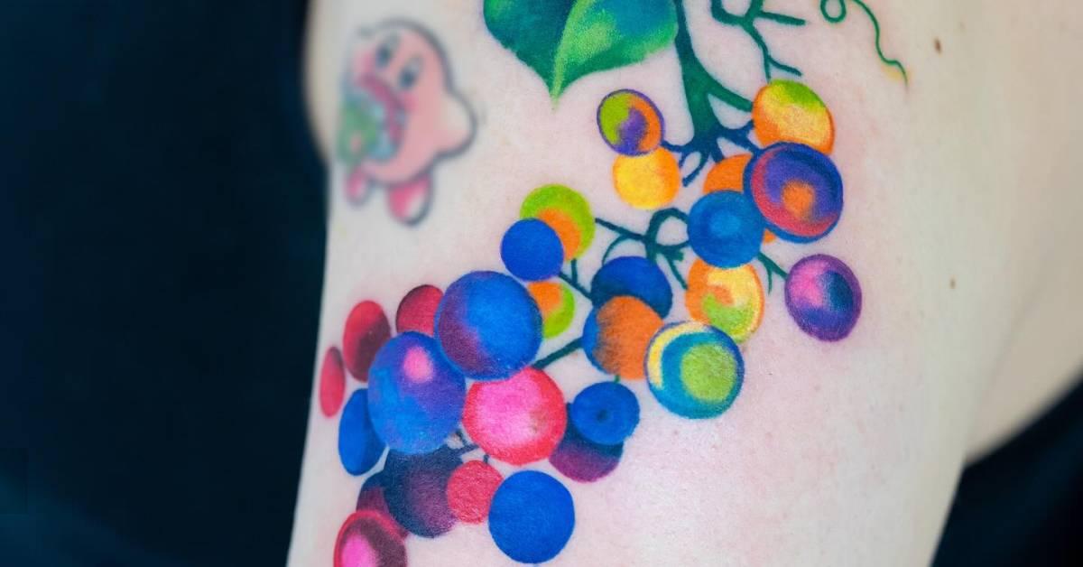 Pop art style grapes tattoo located on the upper arm.