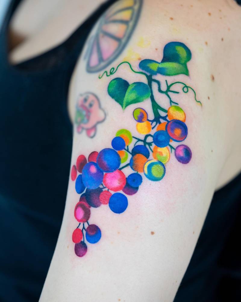Pop art style grapes tattoo located on the upper arm.
