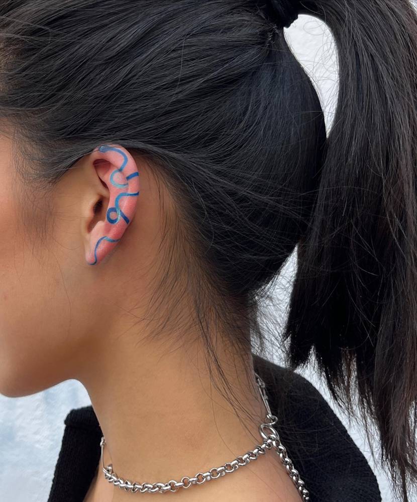 Blue snake tattoo located on the ear.