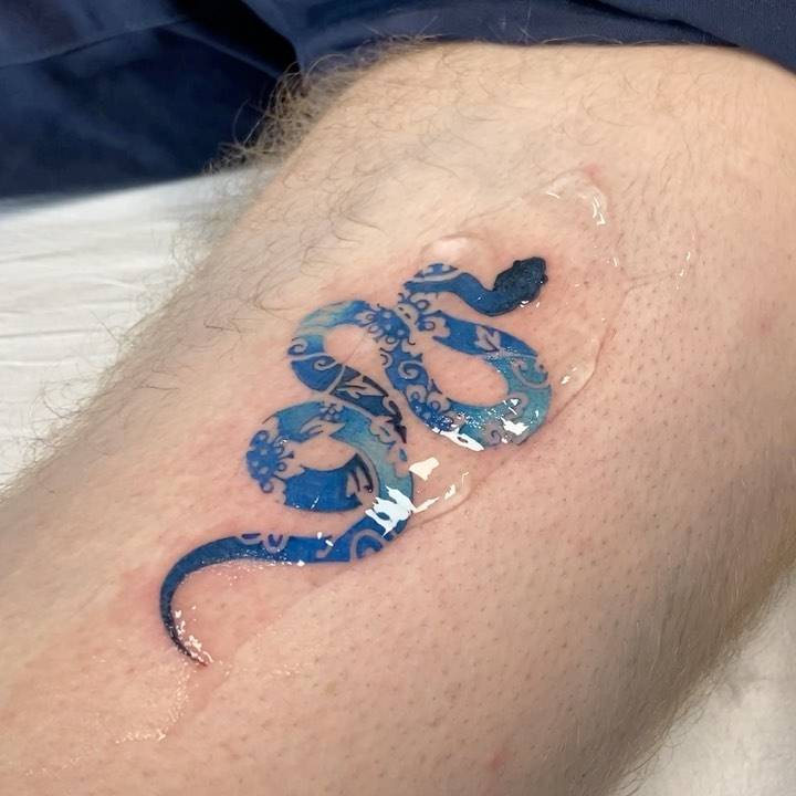 Blue porcelain snake tattoo done on the thigh.