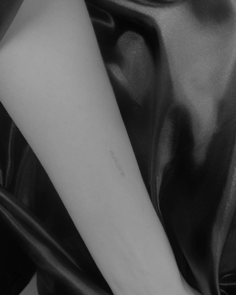 Lettering tattoo of the word "amore" located on the inner forearm.