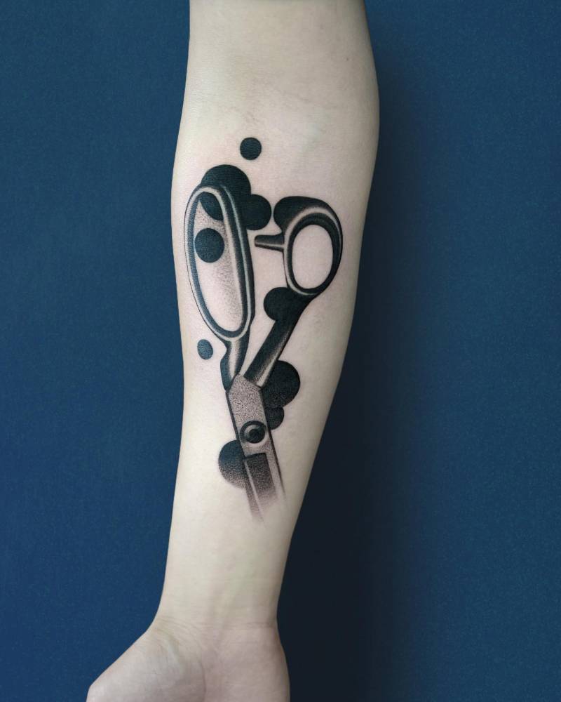 Scissors tattoo located on the inner forearm, blackwork style.