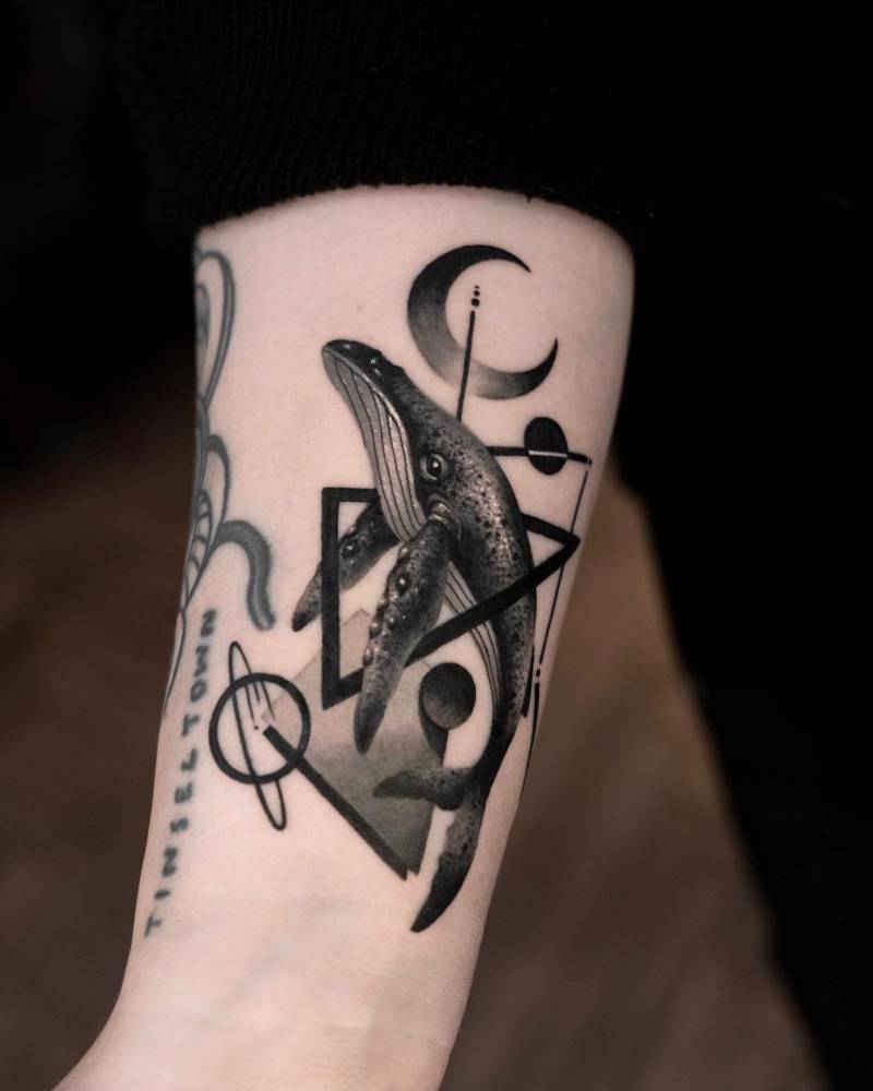 Graphic style whale tattoo located on the wrist.