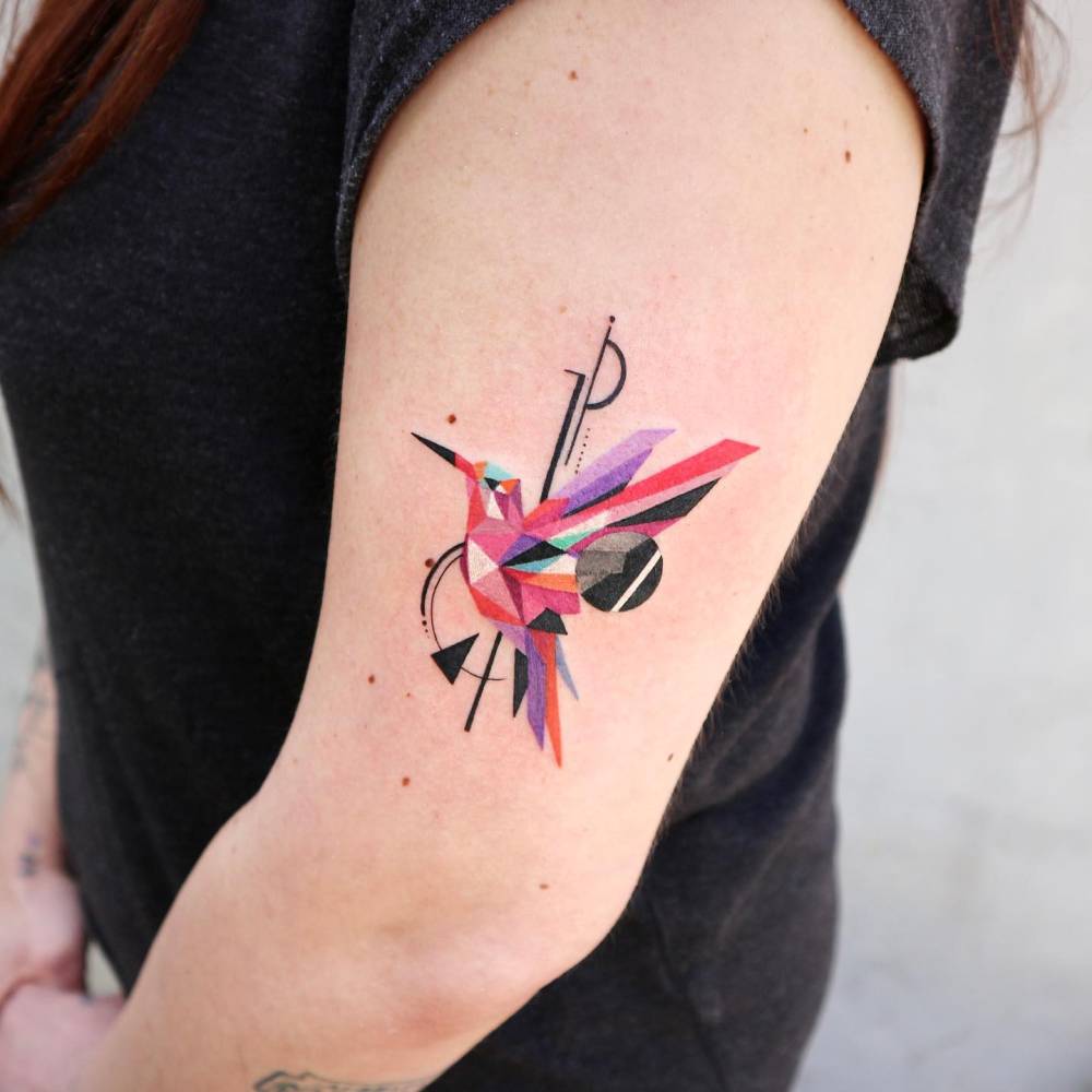 Geometric style hummingbird tattooed on the upper arm.