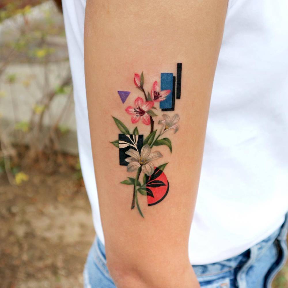 Graphic style lily flowers tattoo done on the upper arm.