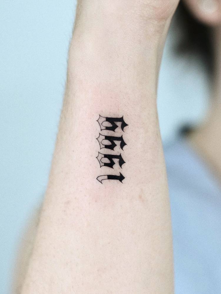 Birth year "1999" tattoo in gothic font placed on the wrist.