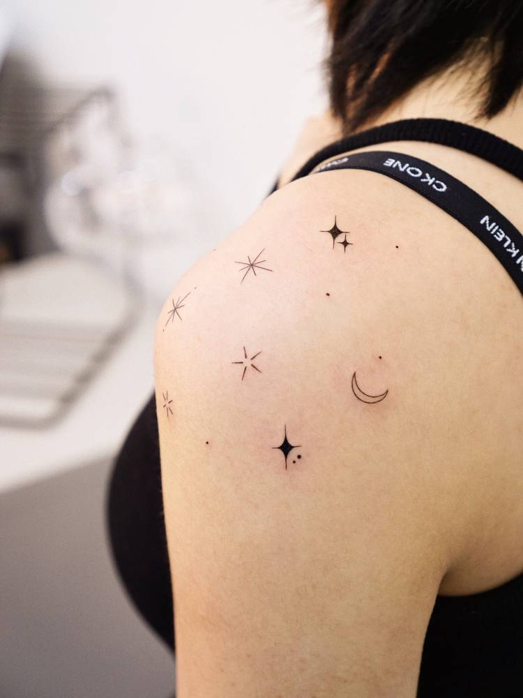 Moon and stars tattoo in minimalistic style located on the shoulder.