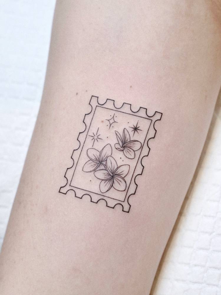 Plumeria stamp tattoo in fine line style located on the inner forearm.