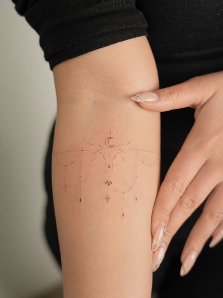Crescent moon and ornaments tattoo located on the inner forearm.