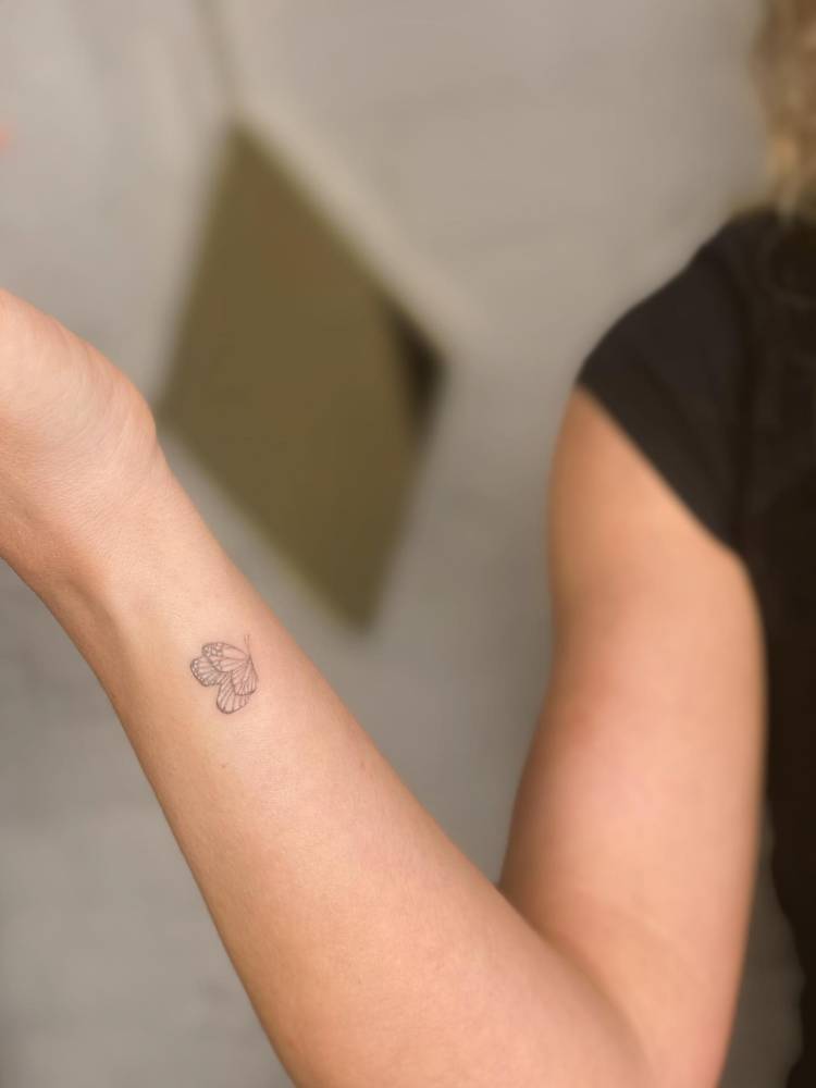 Cute little butterfly tattoo located on the wrist, fine line style.